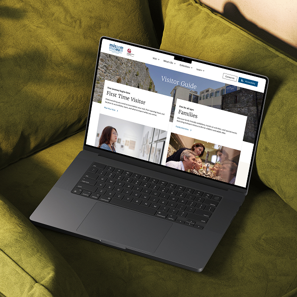 A laptop on a green couch displays a museum website’s visitor guide page built with Simpl by Rob&Paul, featuring sections for first-time visitors and families, plus images and navigation menus at the top.