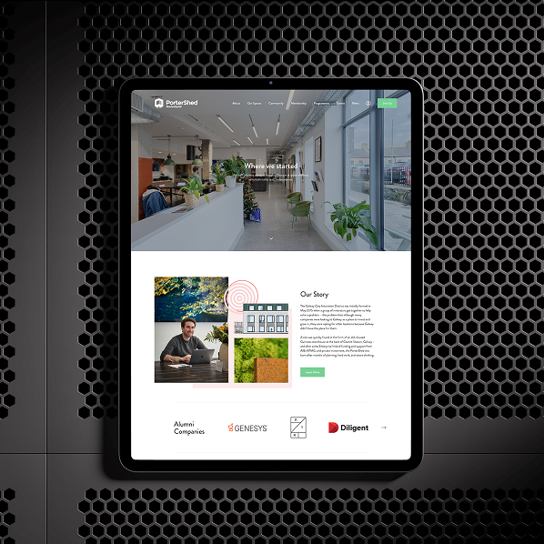 A tablet displays the Simpl by Rob&Paul modern office website, featuring an open workspace photo, a story section with text and images, and alumni company logos, set against a black perforated metal background.