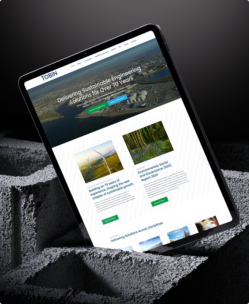 A tablet displays the Tobin engineering homepage, designed with Simpl by Rob&Paul, featuring an aerial view banner, sustainable engineering messaging, and articles on wind energy projects. The tablet rests on a textured grey surface.